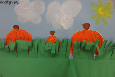 three drawn pumpkins behind paper grass