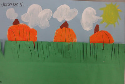 three drawn pumpkins behind paper grass